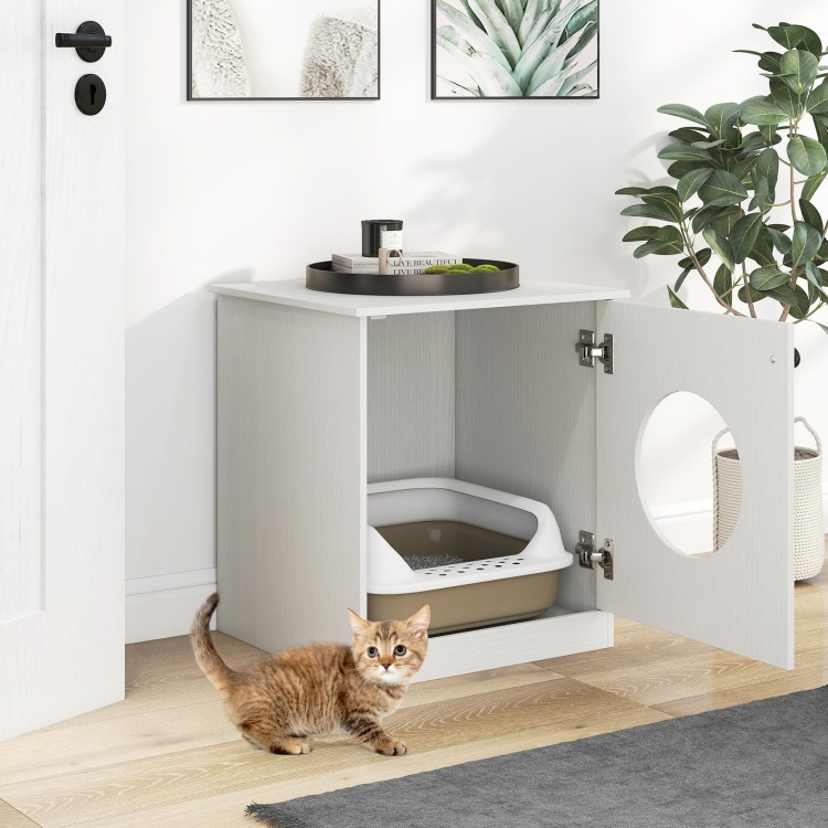 Modern cat litter box enclosure in white, featuring an open door and a playful cat nearby for stylish pet care.