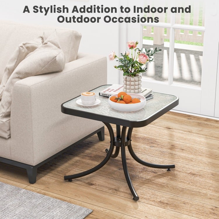 Tempered glass top patio table with heavy-duty metal frame, perfect for indoor and outdoor use by gardens or poolside.