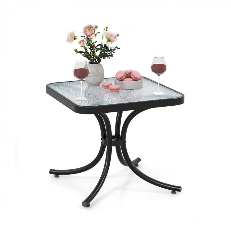 Square patio table with tempered glass top and black metal frame, ideal for garden or poolside use.
