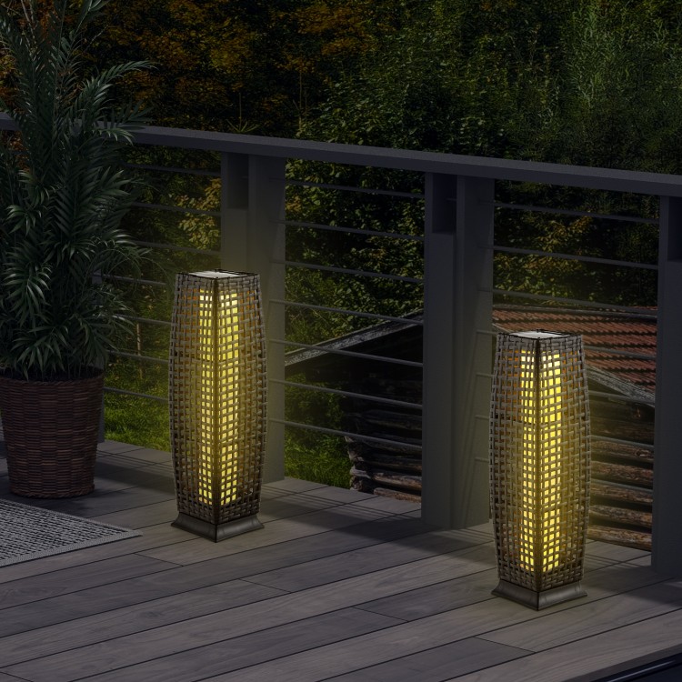 Two solar-powered wicker floor lamps with warm yellow light, perfect for outdoor patios and gardens.