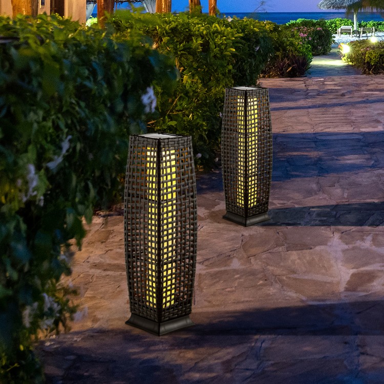 Two solar-powered square wicker floor lamps with warm yellow light, perfect for outdoor patios and gardens.
