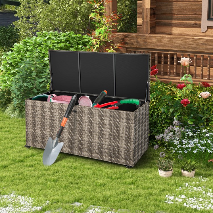 Gray 96-gallon PE wicker outdoor storage box with tools inside, featuring wheels for easy mobility and waterproof liner.