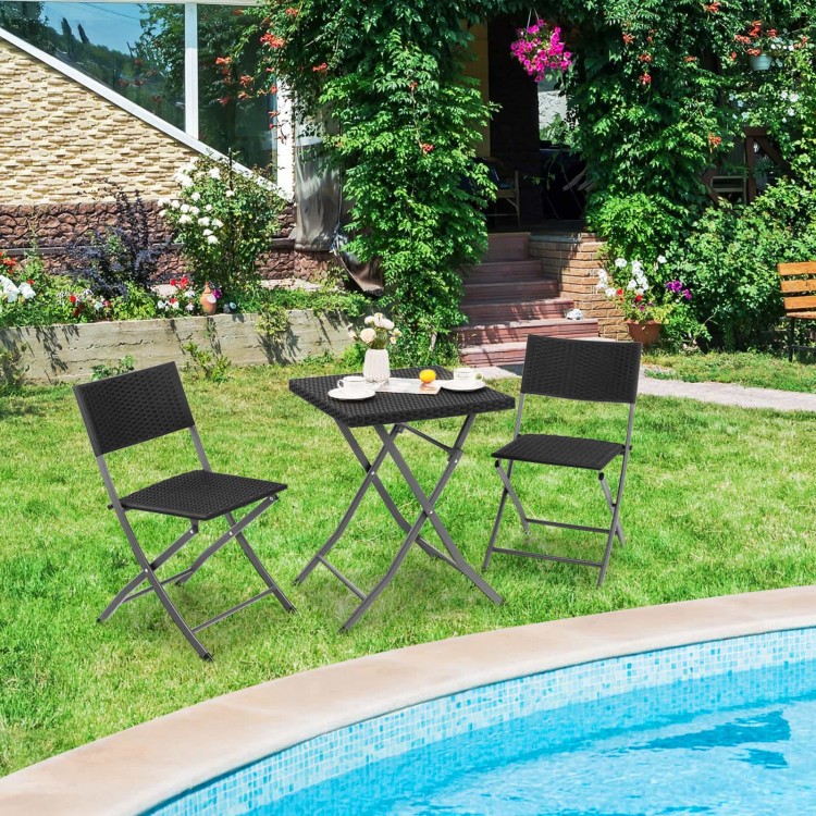 Black folding wicker chairs and table in a patio setting, perfect for outdoor relaxation and space-saving convenience.