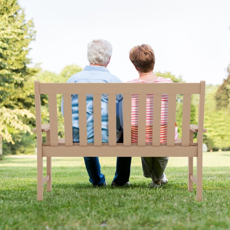 Outdoor 52-inch HDPE bench with backrest and armrests, perfect for two, in a cozy garden setting.