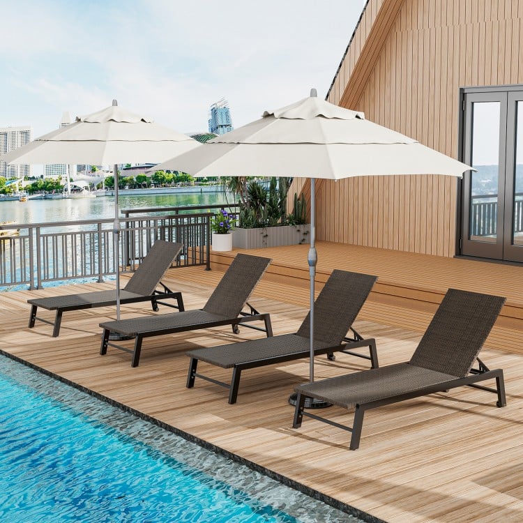 Four brown PE rattan chaise lounges with umbrellas arranged on a wooden deck by the water, perfect for outdoor.