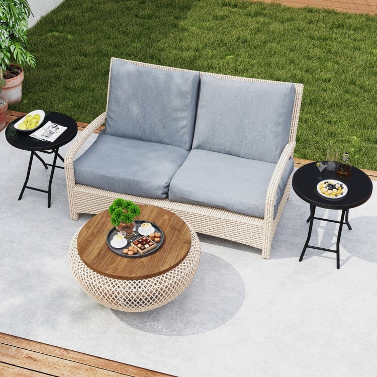 Round black folding side table with tempered glass top, ideal for indoor and outdoor use, shown in a patio setting.