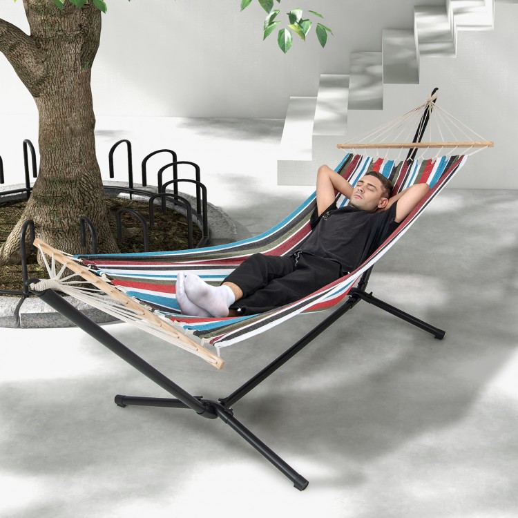 Multicolor hammock with stand, featuring breathable fabric and wood spreader bar, perfect for relaxing in the backyard.