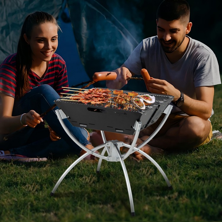 Camping grill with stainless steel grills, set up for BBQ, featuring aluminum legs and a carrying bag for easy.