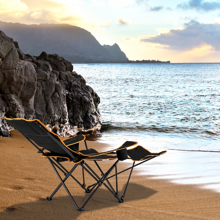 Folding camping chair with footrest and adjustable backrest, perfect for relaxing by the beach or outdoor activities.