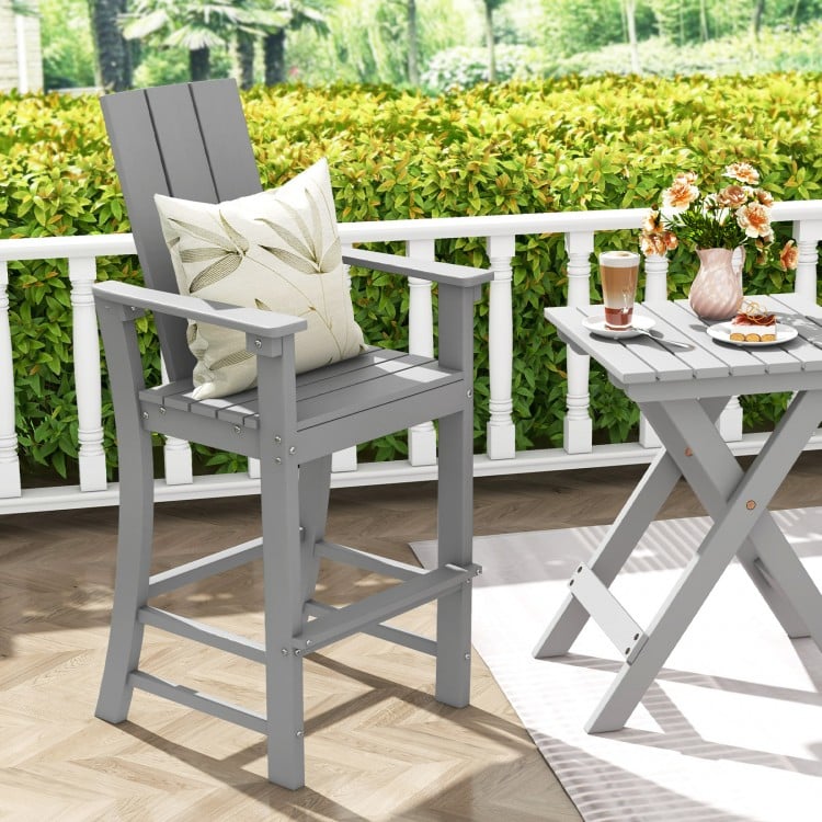 Tall gray Adirondack bar stool with ergonomic backrest, wide armrests, and footrest for outdoor backyard comfort.