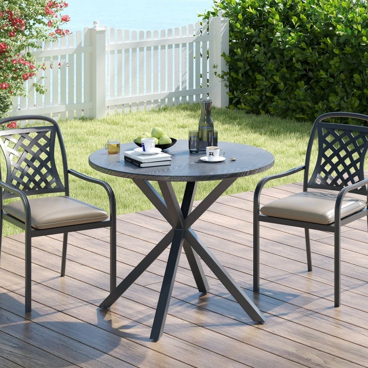 Round patio bistro table with wood-like top and X-shaped legs, ideal for outdoor dining in gardens or yards.