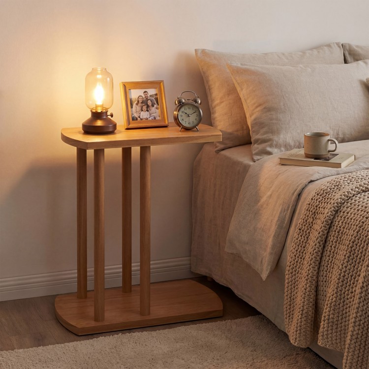 Narrow C-shaped teak wood side table with thickened top, featuring a lamp and clock, perfect for bedside use.