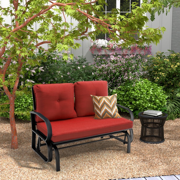 Brick red cushioned 2-person glider bench with ergonomic armrests, perfect for outdoor patio relaxation.