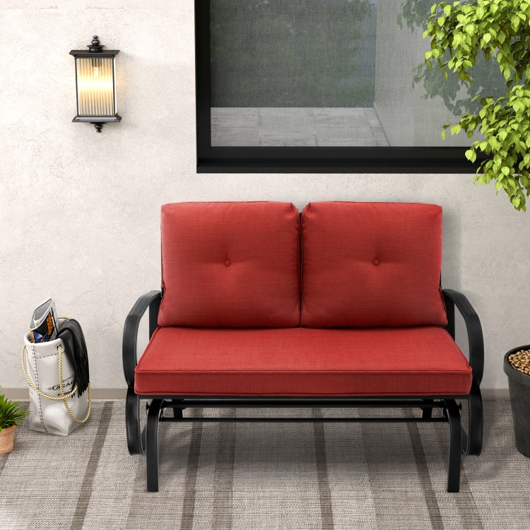 Brick red cushioned 2-person glider bench with ergonomic armrests, perfect for patio or garden relaxation.