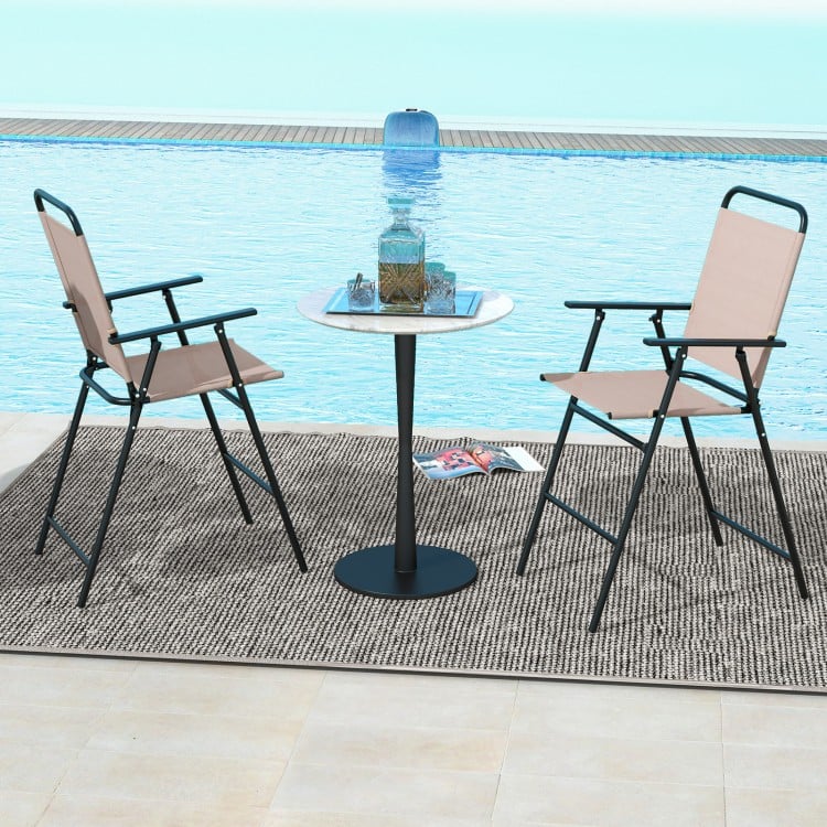 Set of 2 beige patio folding bar-height chairs with armrests, placed by a poolside for outdoor relaxation.