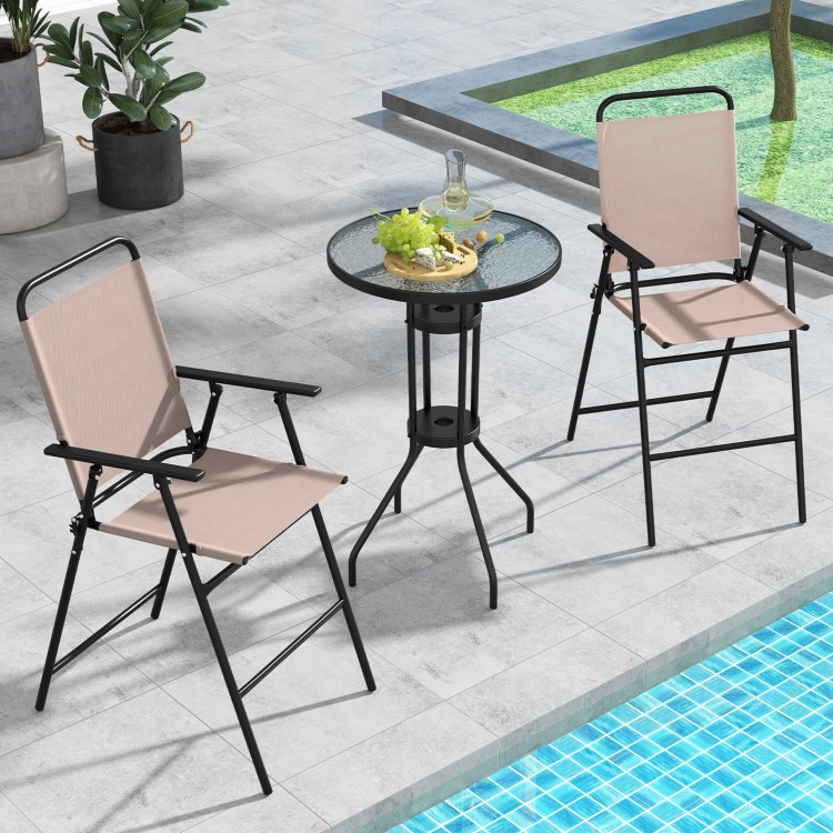 Two beige folding chairs and a round glass table in an outdoor bistro set, ideal for patio or poolside use.