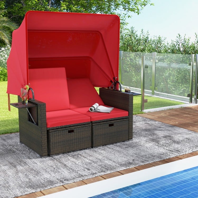 Outdoor patio rattan daybed with retractable canopy and adjustable backrests in red, perfect for poolside relaxation.