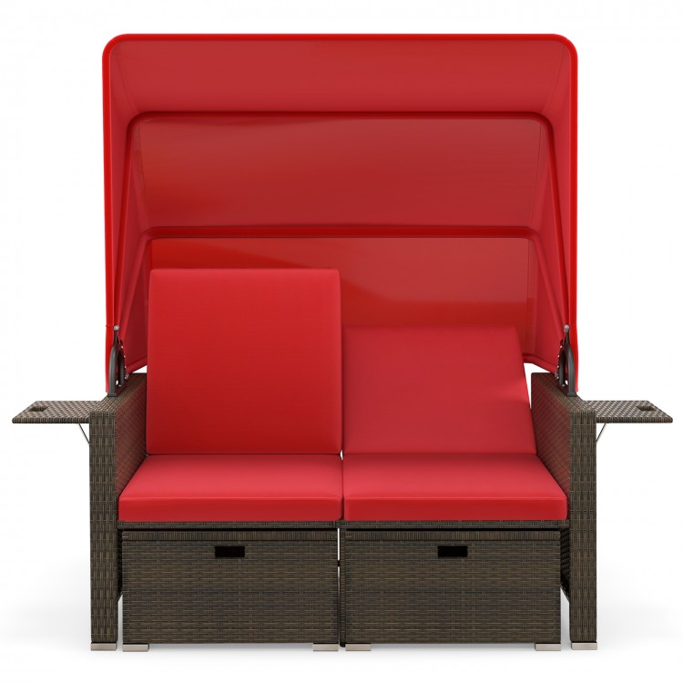 Outdoor patio rattan daybed with red cushions, retractable canopy, and adjustable backrests for backyard relaxation.