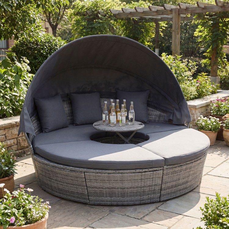 Round outdoor daybed with retractable canopy, gray PE wicker, and cushions, perfect for backyard relaxation.