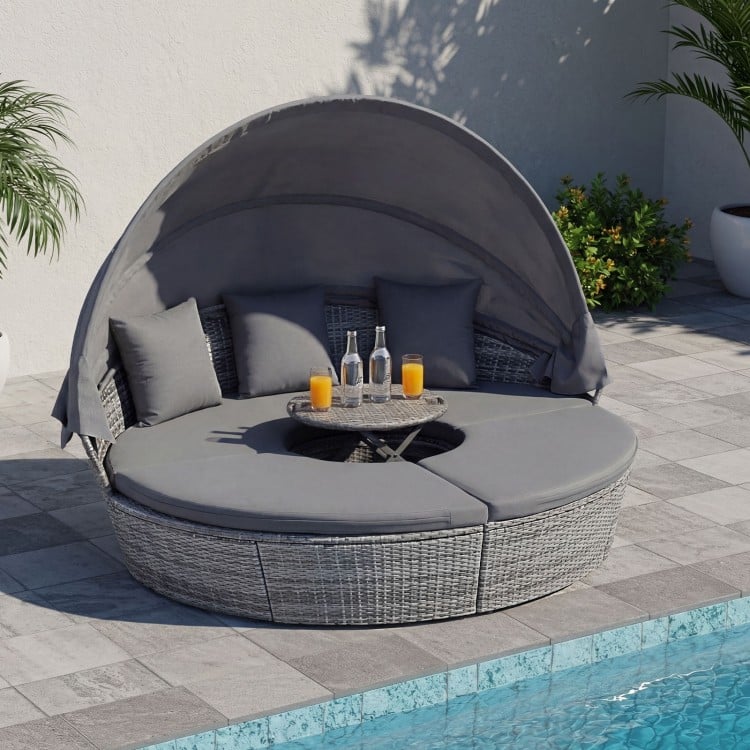 Round outdoor daybed with retractable canopy and gray cushions, perfect for poolside relaxation and comfort.