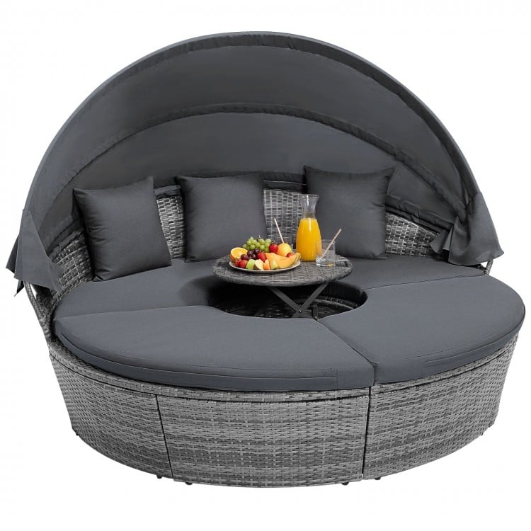 Round outdoor daybed with retractable canopy and gray cushions, perfect for backyard relaxation and sunbathing.
