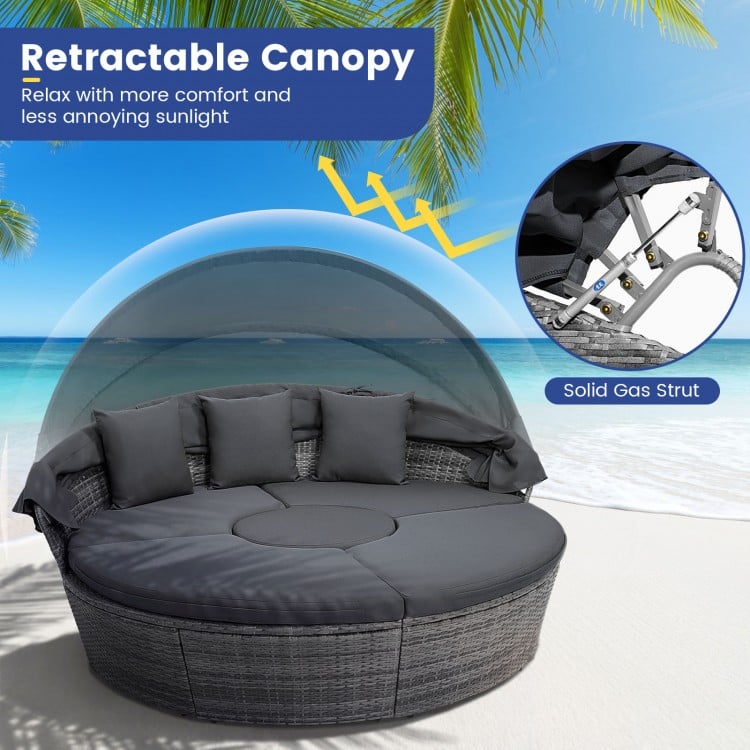 Outdoor PE wicker round daybed with retractable canopy and gray cushions, ideal for backyard relaxation and sun.
