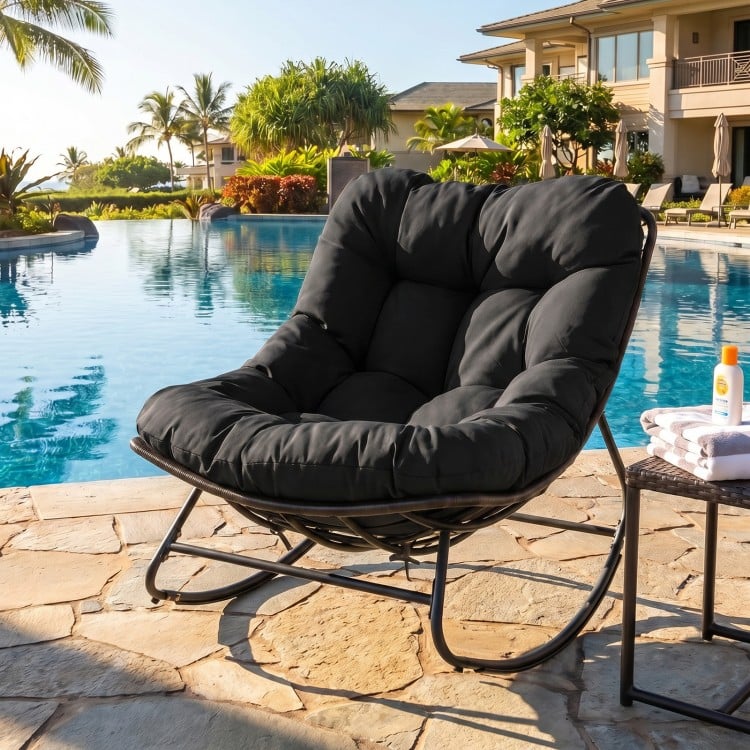 Black outdoor Papasan rocking chair with thick cushion, designed for comfort and stability by the poolside.