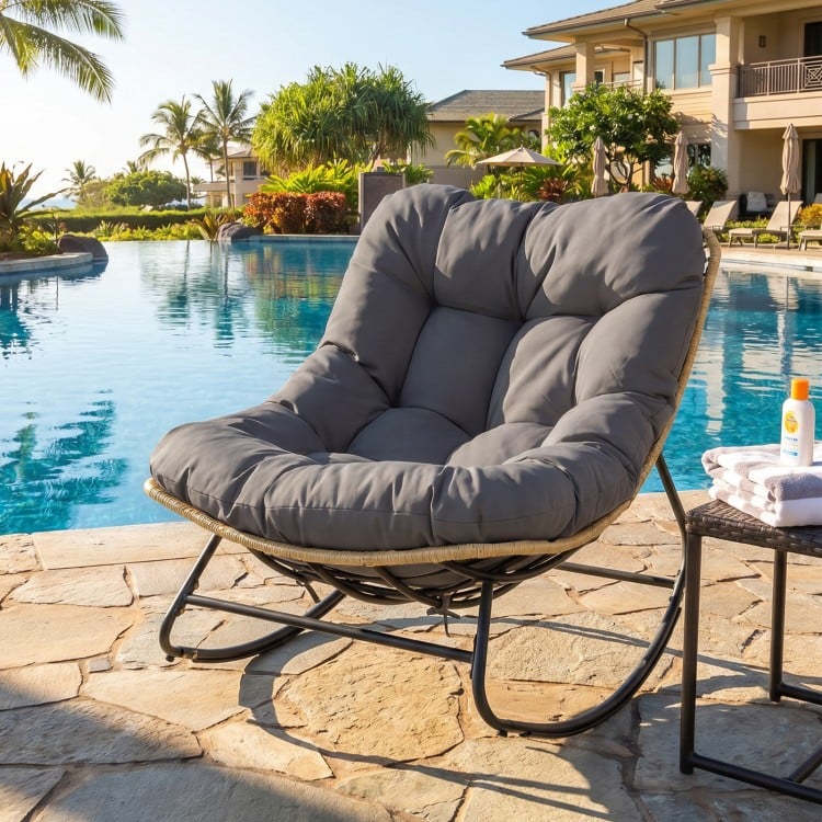 Outdoor Papasan rocking chair with thick gray cushion, ergonomic design for patio relaxation by the pool.