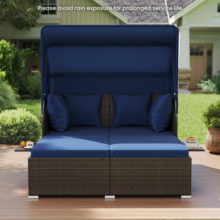Outdoor patio rattan daybed in navy with retractable canopy and side tables, perfect for backyard relaxation.