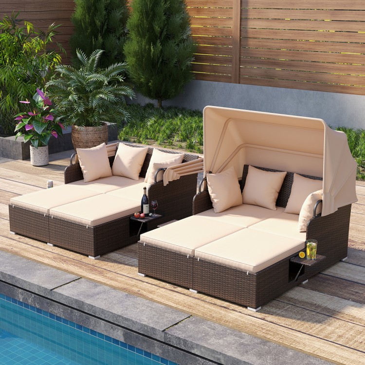 Outdoor patio rattan daybed with retractable canopy, beige cushions, and side tables, perfect for poolside relaxation.