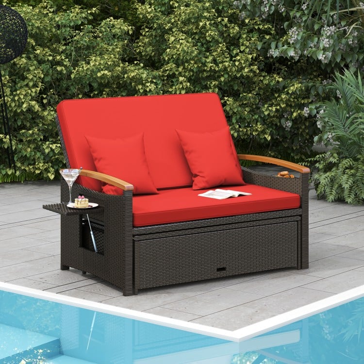 Red outdoor wicker loveseat daybed with cushions, folding panels, and storage ottoman for patio relaxation.