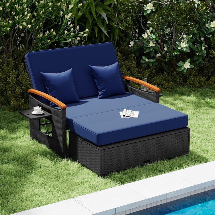 Luxurious outdoor wicker daybed in dark blue with soft cushions and a convenient storage ottoman for stylish patio.