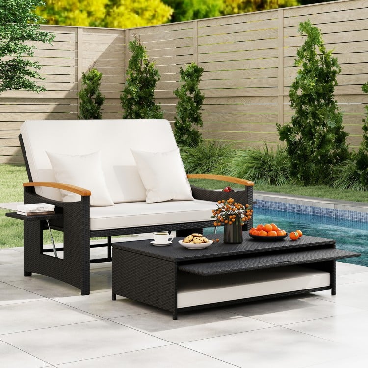 Outdoor wicker daybed set with white cushions and wooden armrests, featuring a coffee table for stylish patio lounging.