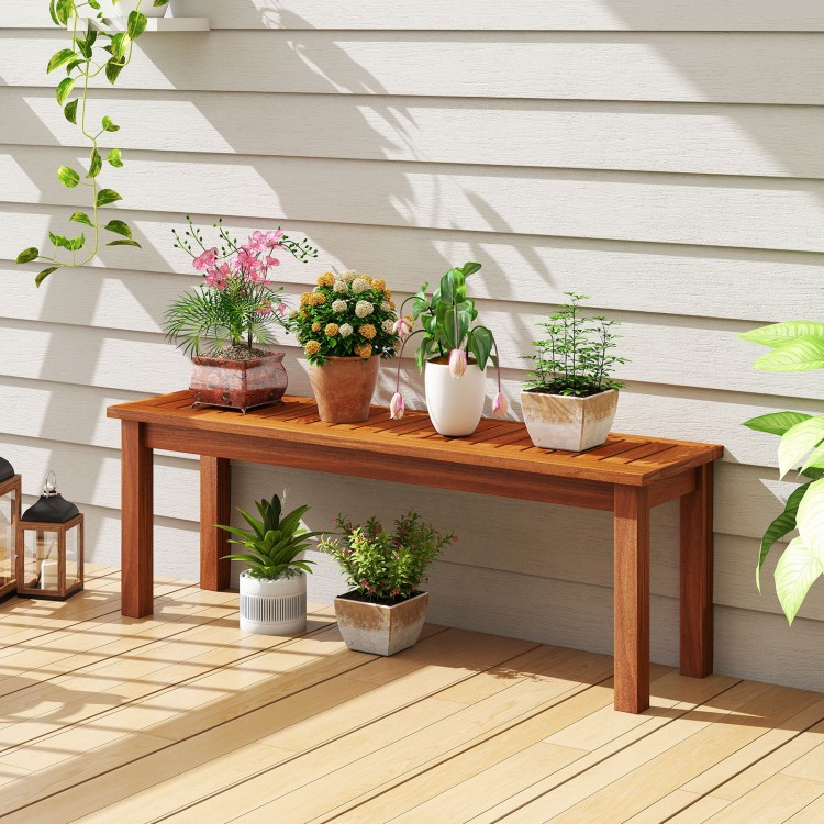 Backless outdoor wood bench with slatted seat, perfect for patio or garden, showcasing plants and flowers.
