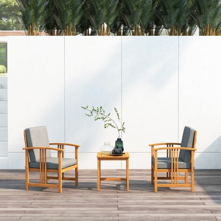 Two chairs with gray cushions and a coffee table made of acacia wood, perfect for outdoor patio relaxation.