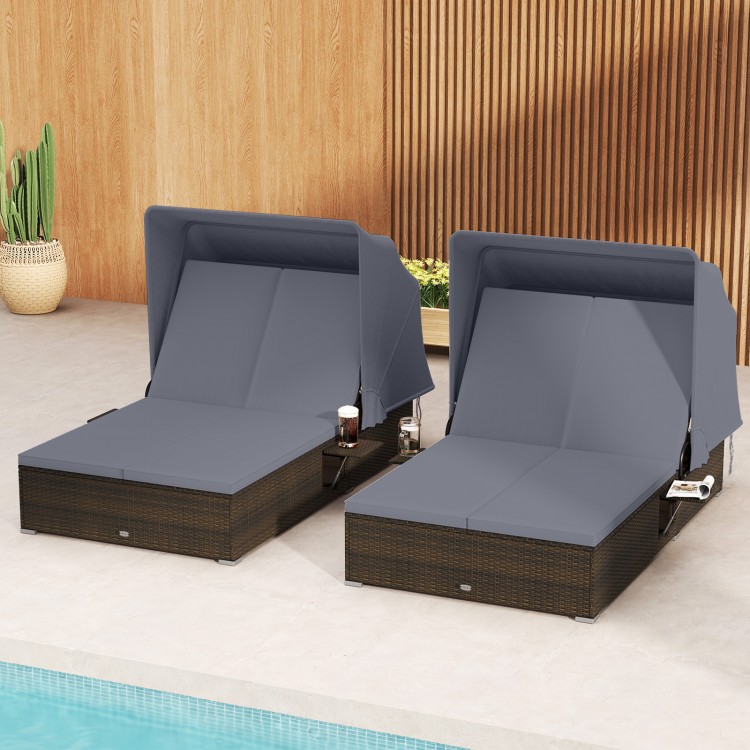Patio double chaise lounge in gray with adjustable backrests, retractable canopy, and folding side trays for poolside.