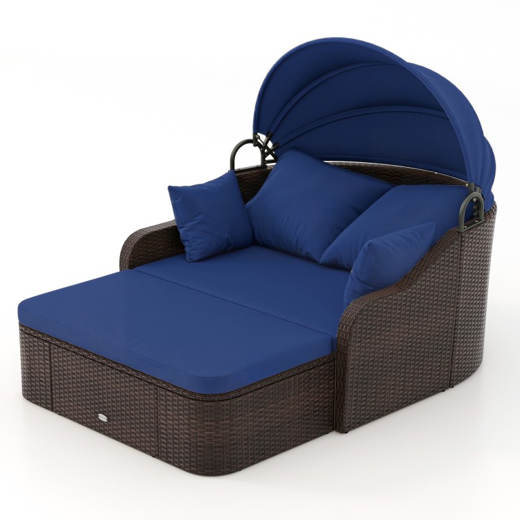 Patio PE rattan daybed with retractable canopy and navy cushions, perfect for lounging by the poolside or garden.