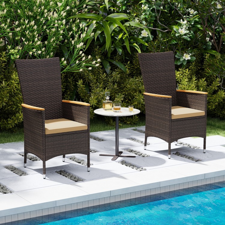 Two outdoor wicker dining chairs with high backrests, featuring beige cushions, set by a poolside for stylish.