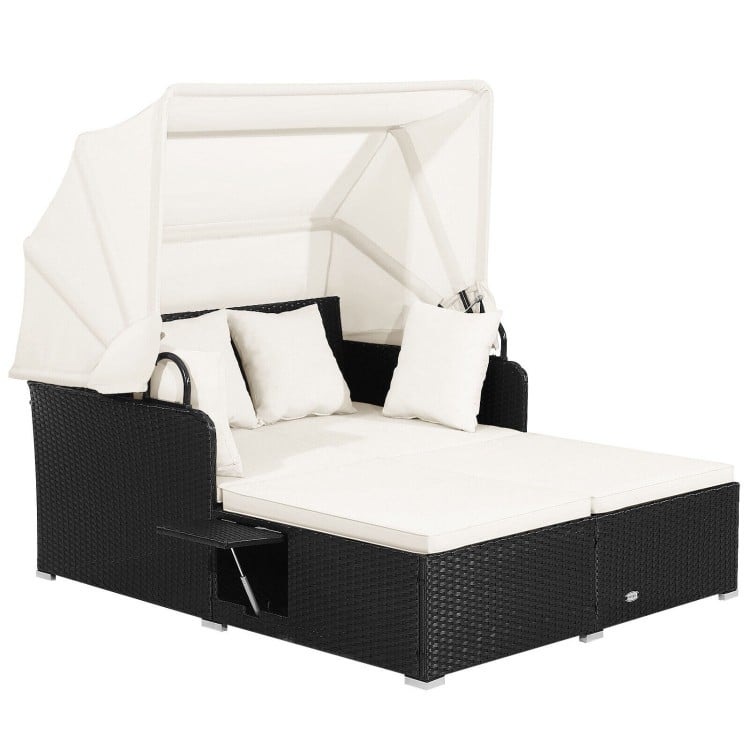 Patio rattan daybed with retractable canopy, soft cushions, and side tables for outdoor relaxation by the poolside.