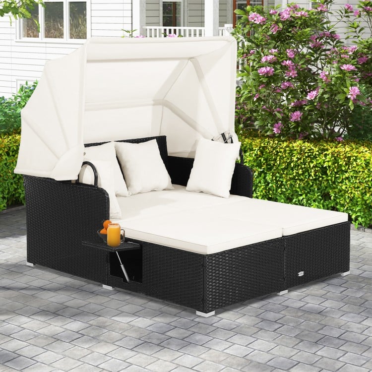 Patio rattan daybed with retractable canopy and side tables in off-white, perfect for backyard relaxation.