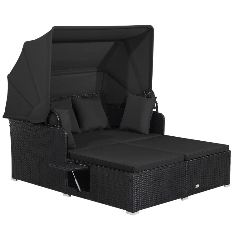 Patio rattan daybed with retractable canopy, soft black cushions, and side tables, perfect for outdoor relaxation.