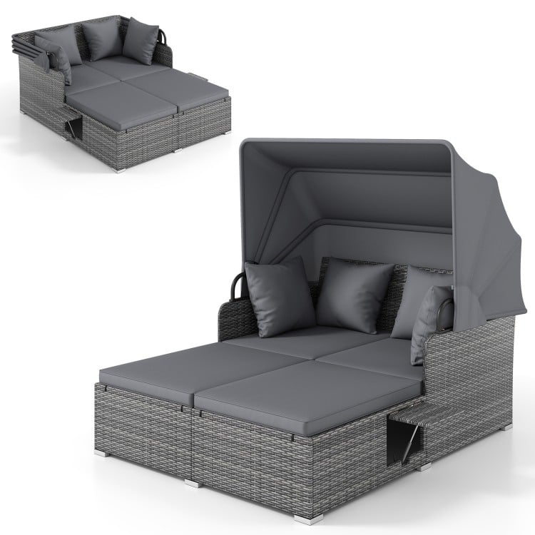 Patio rattan daybed with retractable canopy and soft cushions, featuring foldable side tables for outdoor relaxation.