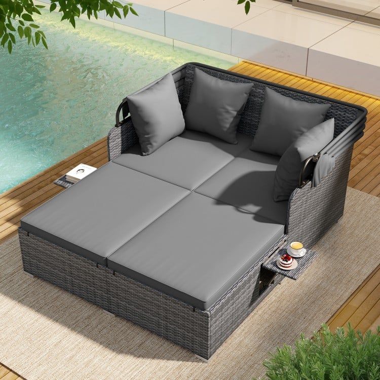 Patio rattan daybed in mix gray with soft cushions, retractable canopy, and foldable side tables for outdoor relaxation.