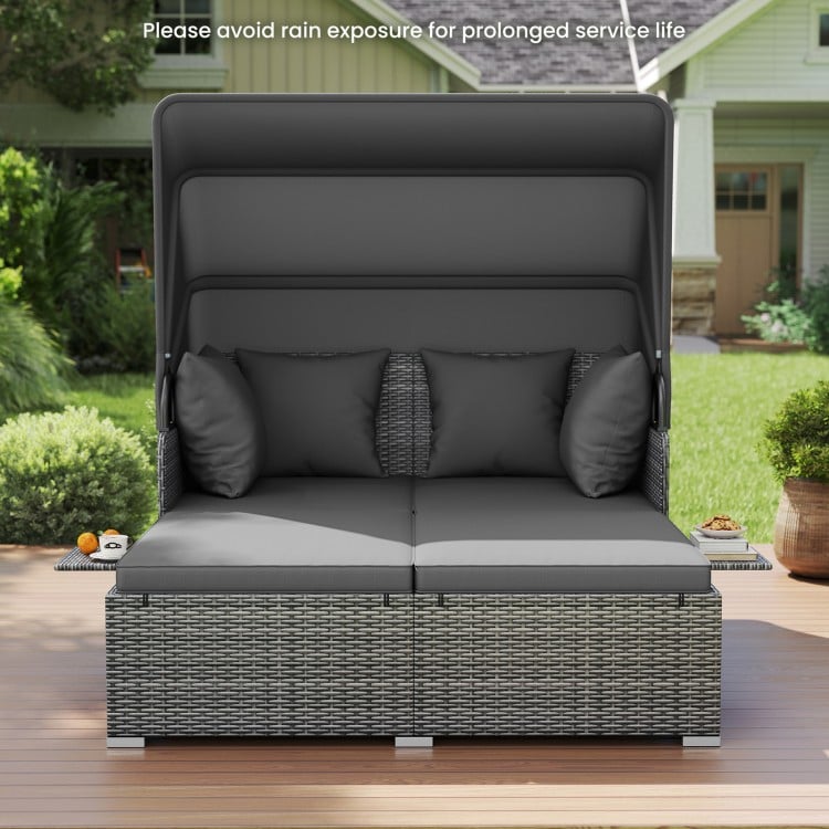 Patio rattan daybed with retractable canopy, soft cushions, and side tables in mix gray for outdoor relaxation.