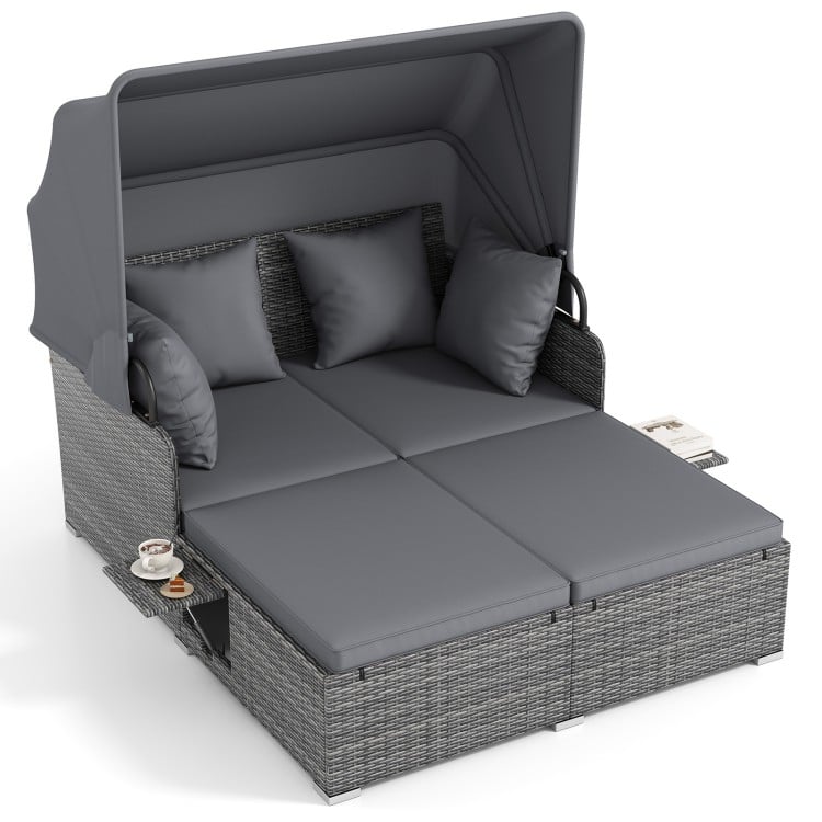 Patio rattan daybed with retractable canopy, gray cushions, and side tables, perfect for outdoor relaxation.