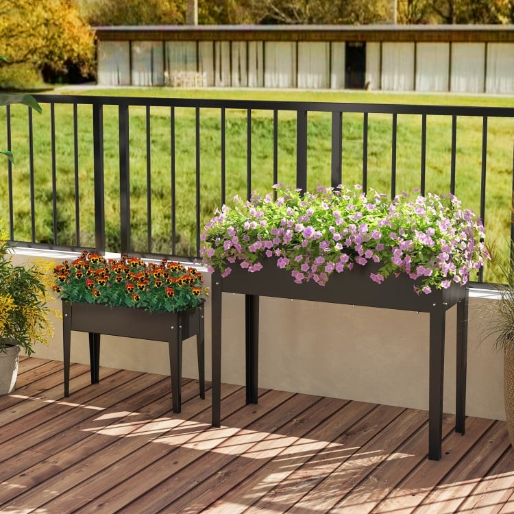 Elevated metal planter box set with legs, featuring drainage holes for healthy plant growth on a balcony.