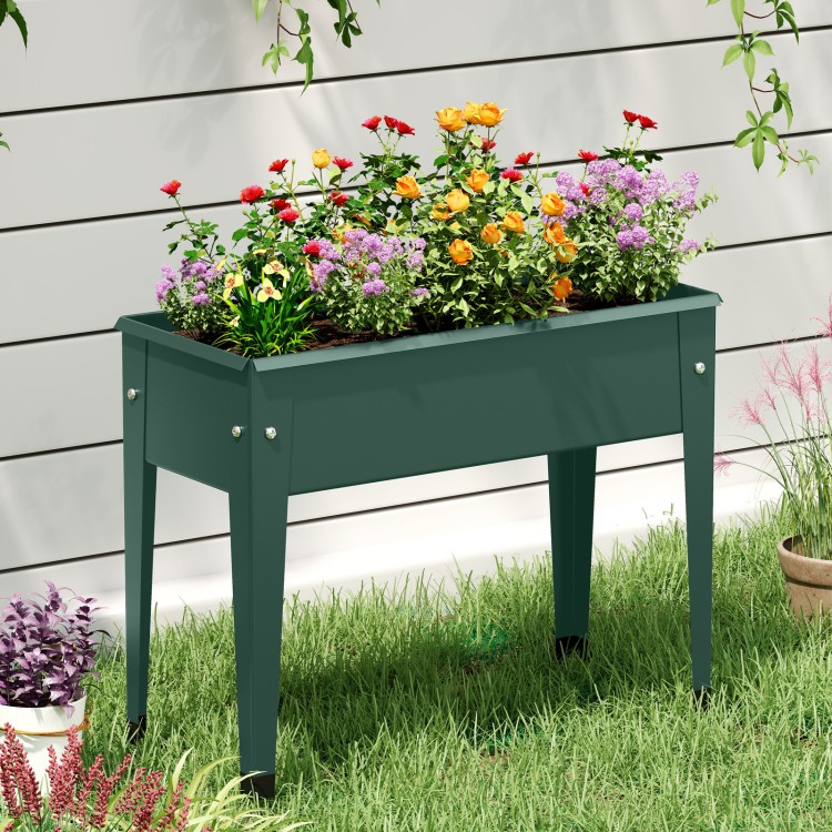 Elevated green metal gardening box with legs, featuring vibrant flowers, perfect for cultivating plants and herbs.