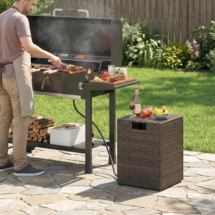 Rattan propane tank cover side table in brown with flip-top lid, ideal for patio and garden storage.