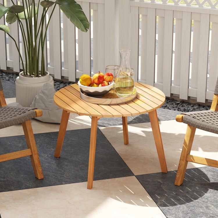 Round outdoor acacia wood side table with slatted tabletop, ideal for patio or garden use, featuring a natural finish.