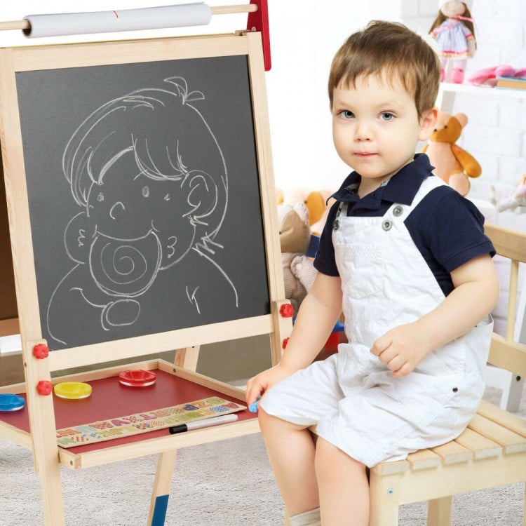 Kid sitting beside a height-adjustable wooden art easel with chalkboard and magnetic stickers for creative play.